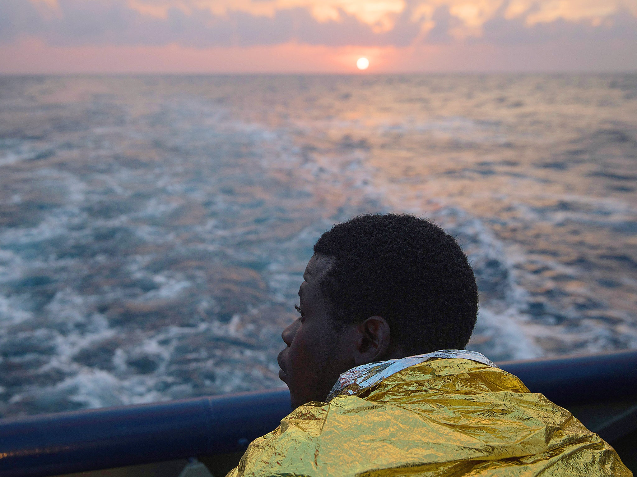 A young refugee looks across the water