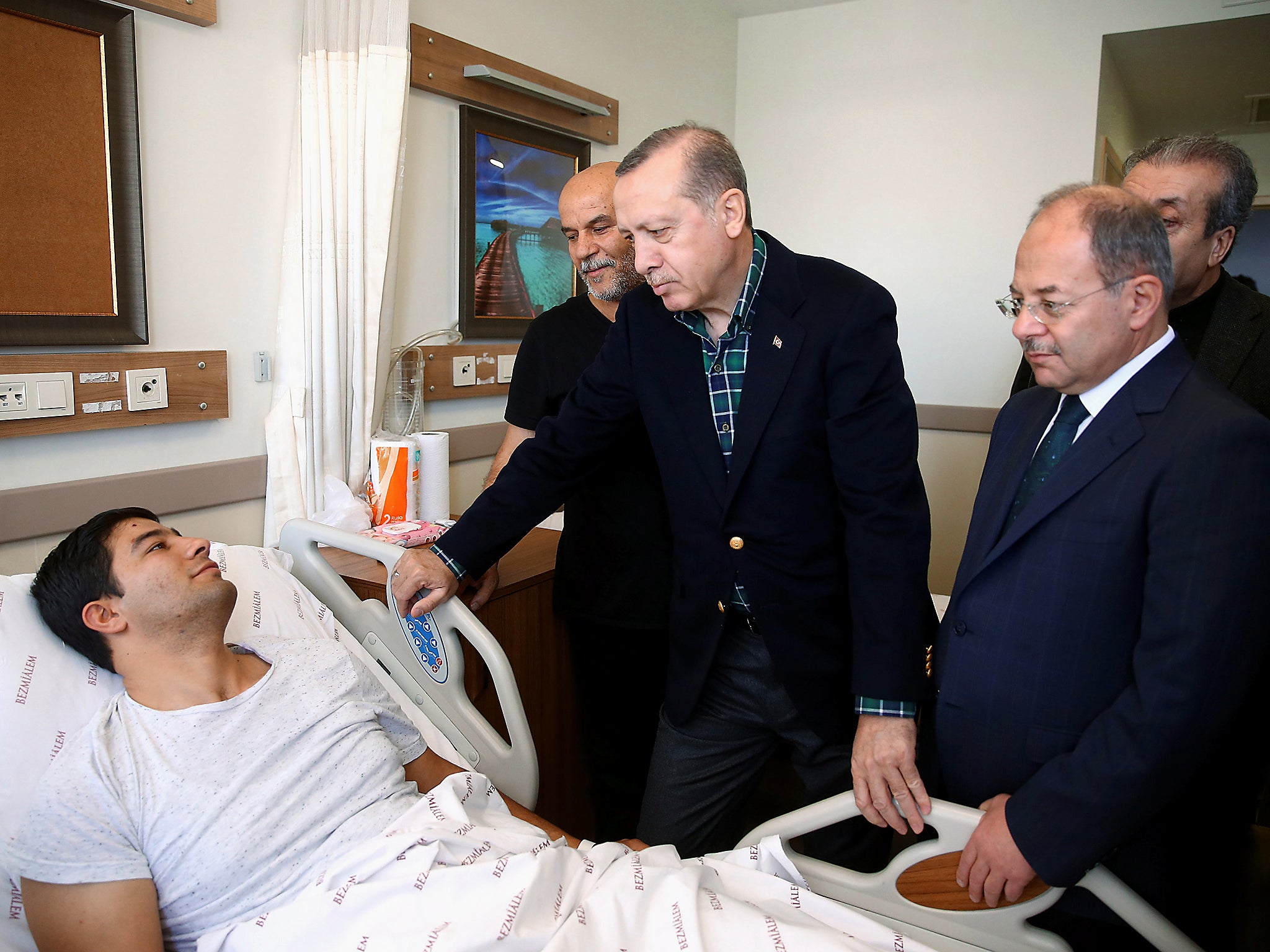 Turkish President Tayyip Erdogan visits a police officer who was injured in Saturday's blasts in a hospital in Istanbul, Turkey