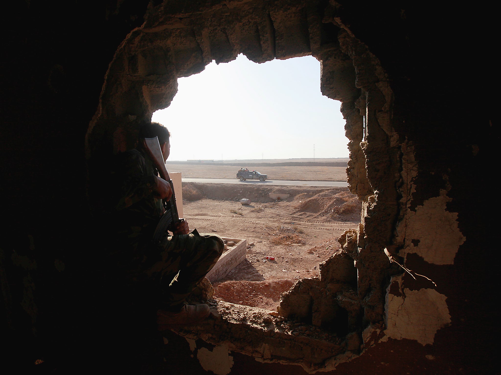 Policemen look through a hole in a house from the clashes in Qaraqosh, near Mosul, Iraq