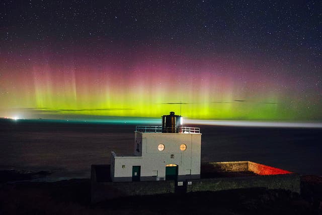 The Northern Lights appearing in the sky over Bamburgh lighthouse in Northumberland in December