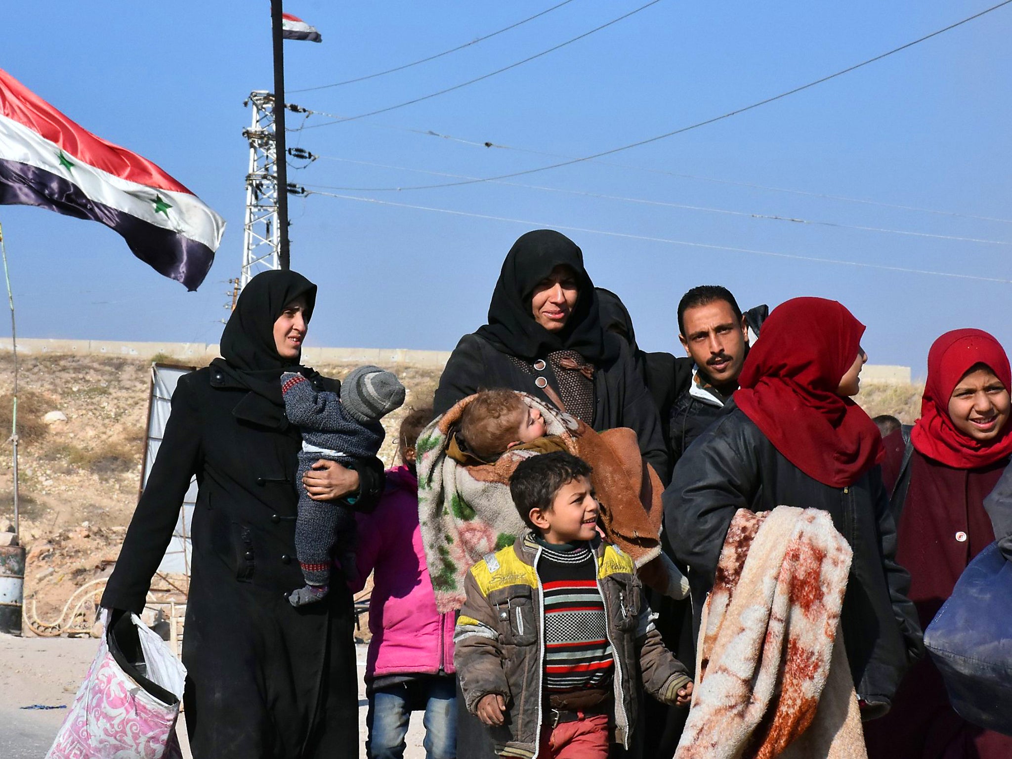 A Syrian family arrives at a checkpoint, manned by pro-government forces, at the al-Hawoz street roundabout, after leaving Aleppo's eastern neighbourhoods