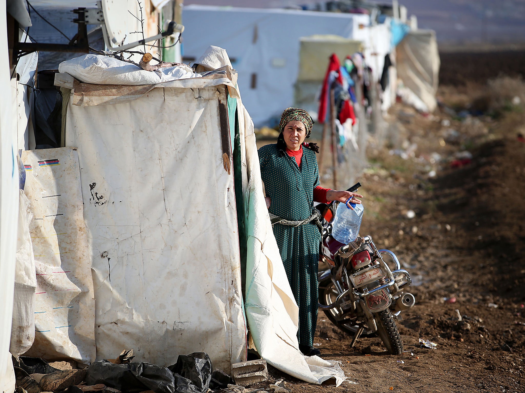 A Syrian refugee woman outside the entrance to a refugee tent