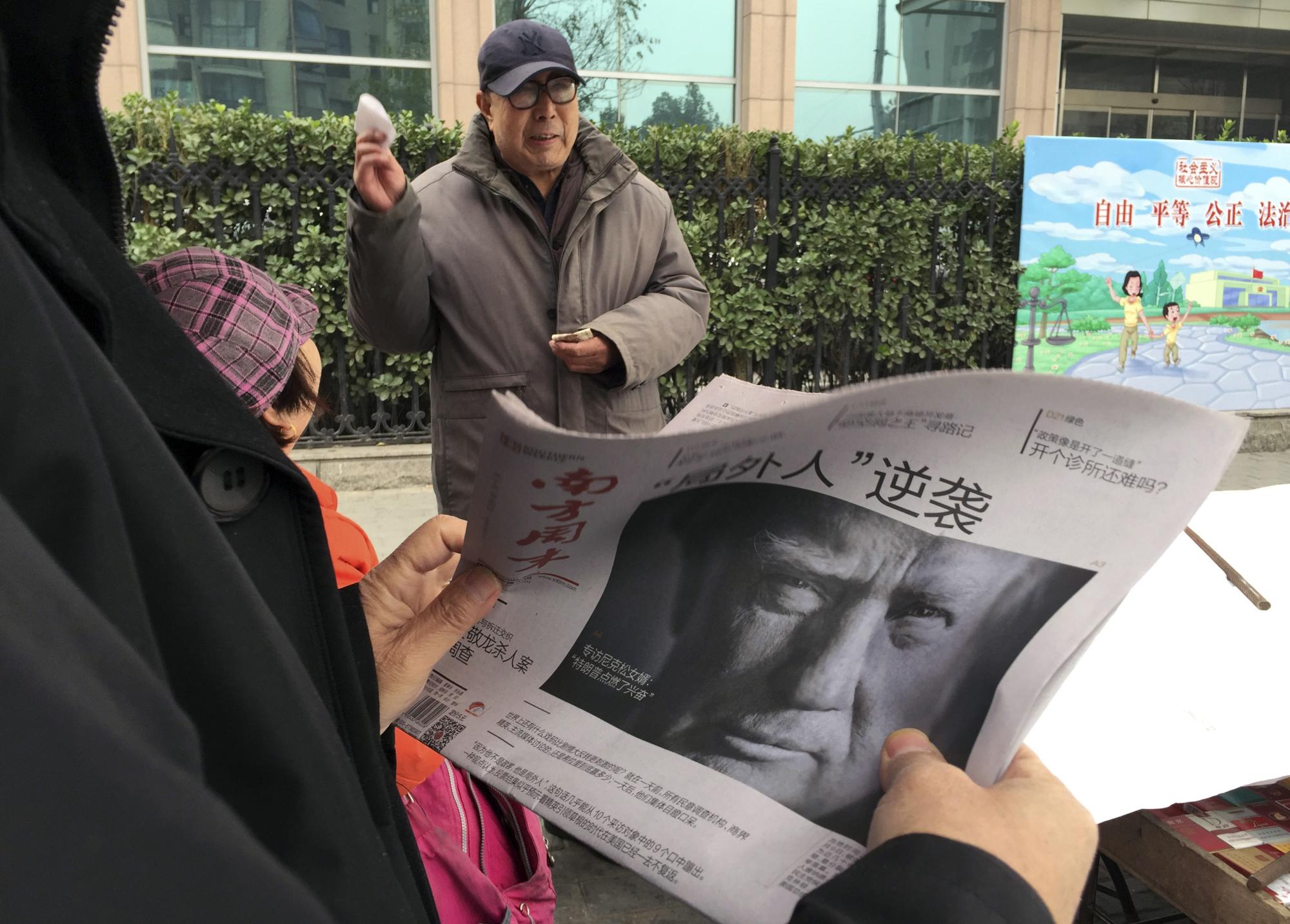 A Chinese man holds up a Chinese newspaper with the front page photo of US President-elect Donald Trump