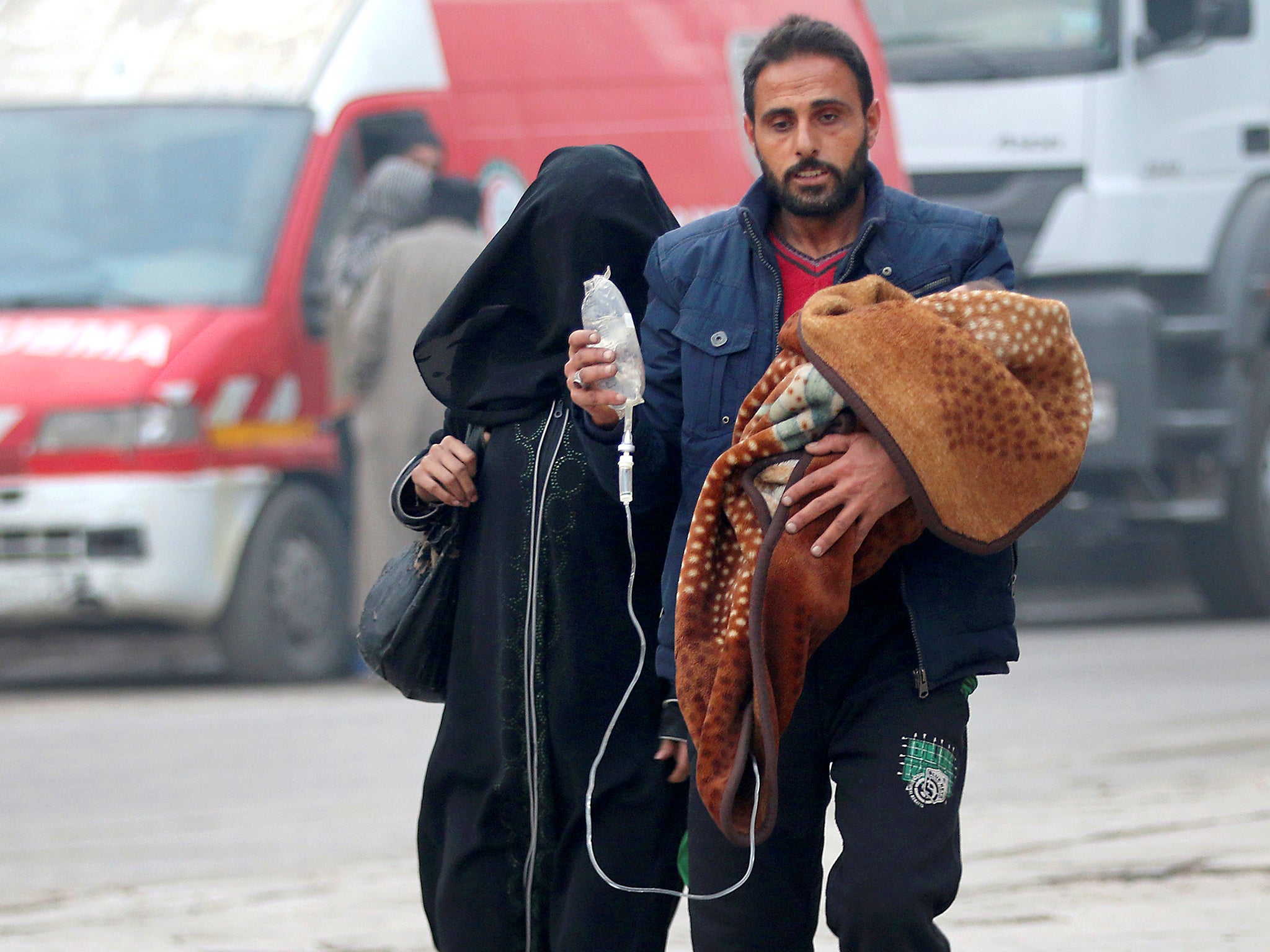 A man carries a child with an IV drip as he flees deeper into the remaining rebel-held areas of Aleppo, Syria