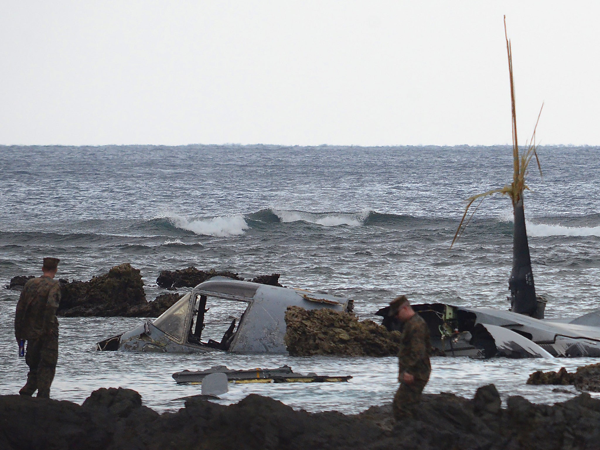 The wreckage of a US Marine MV-22 Osprey tilt-rotor aircraft is seen as the tide recedes on the coast of Nago, Japan's southern island of Okinawa, after it crash landed in shallow waters