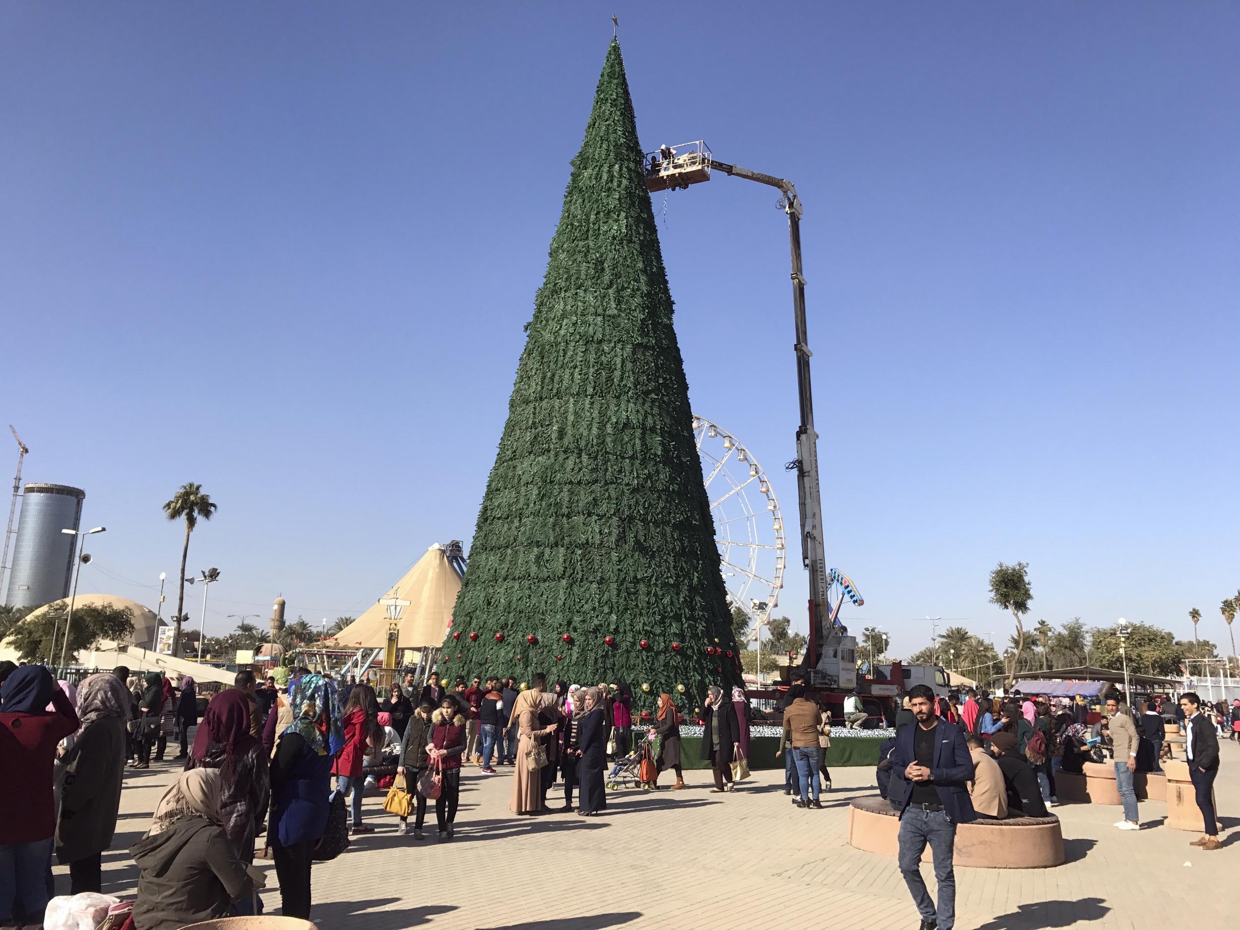 Workers use a crane to mount a large Christmas tree in al-Zawra Park in Baghdad