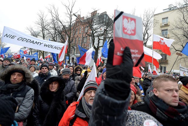 People hold banners reading 'We will not give Freedom' and hold up copies of the Polish constitution as they take part in a demonstration on 18 December, 2016