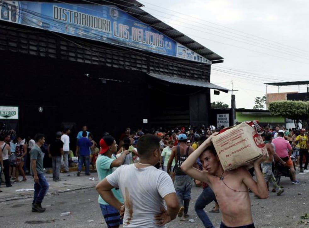 People carry goods taken from a food wholesaler after it was broken into during a riot in La Fria, Venezuela on 17 December