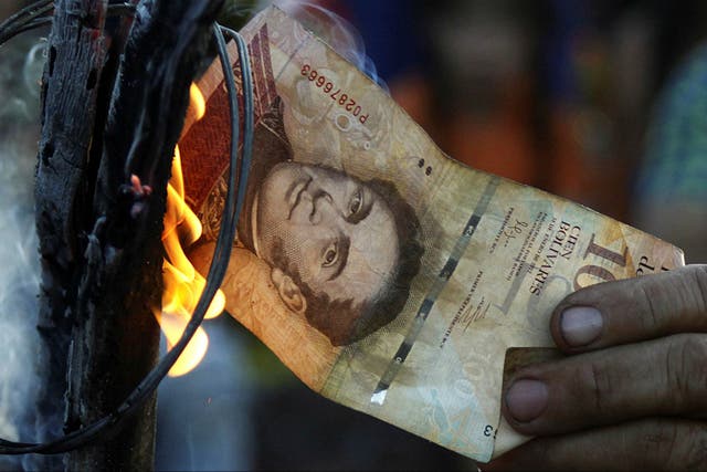 A man burns a 100-bolivar bill during a protest in El Pinal, in the northwest of Venezuela