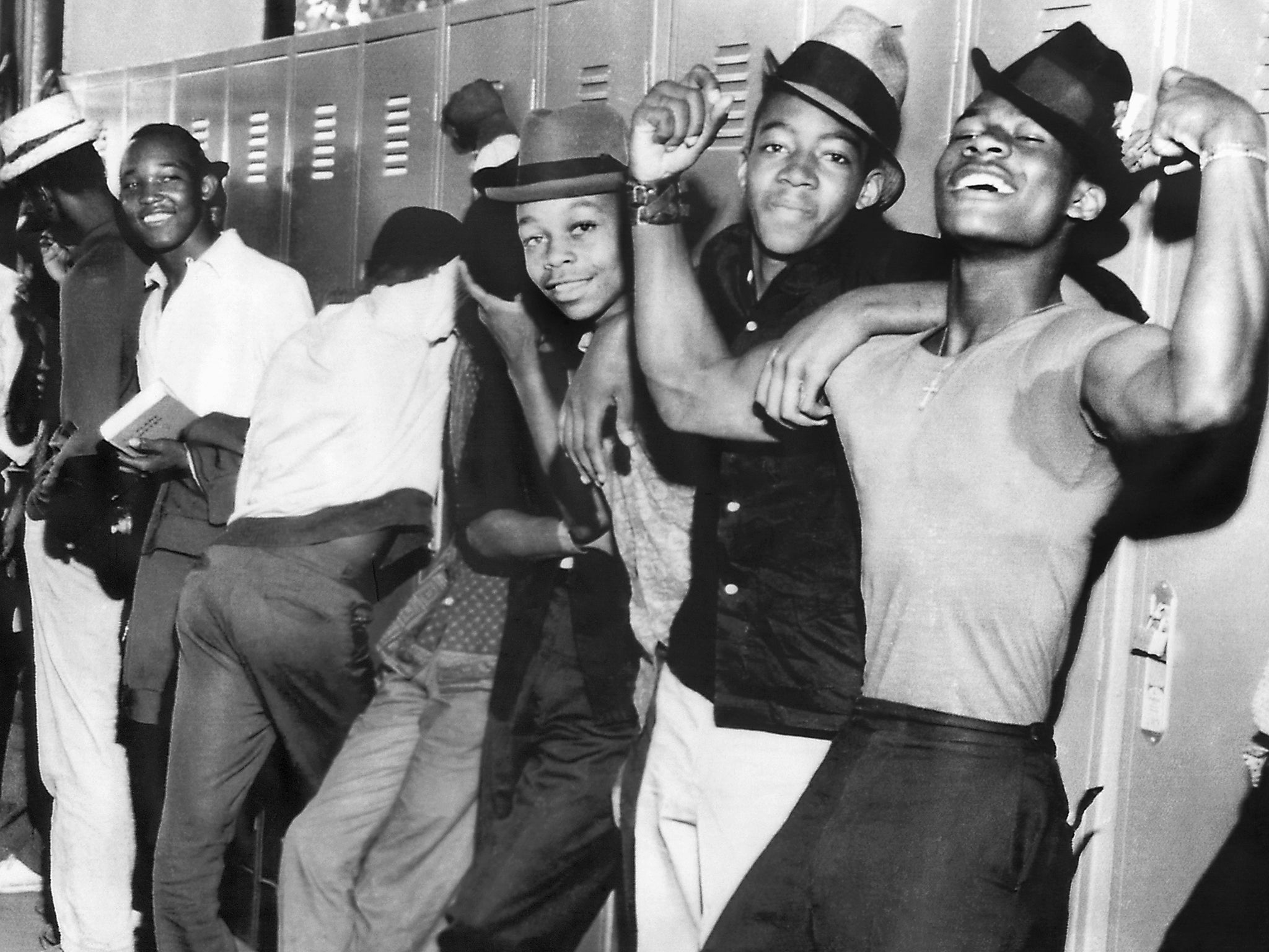 A member of a gang of Negro youths flexes his muscles while waiting to be interrogated by police as volence continued after the fatal shooting of a Negro boy stirred racial tensions