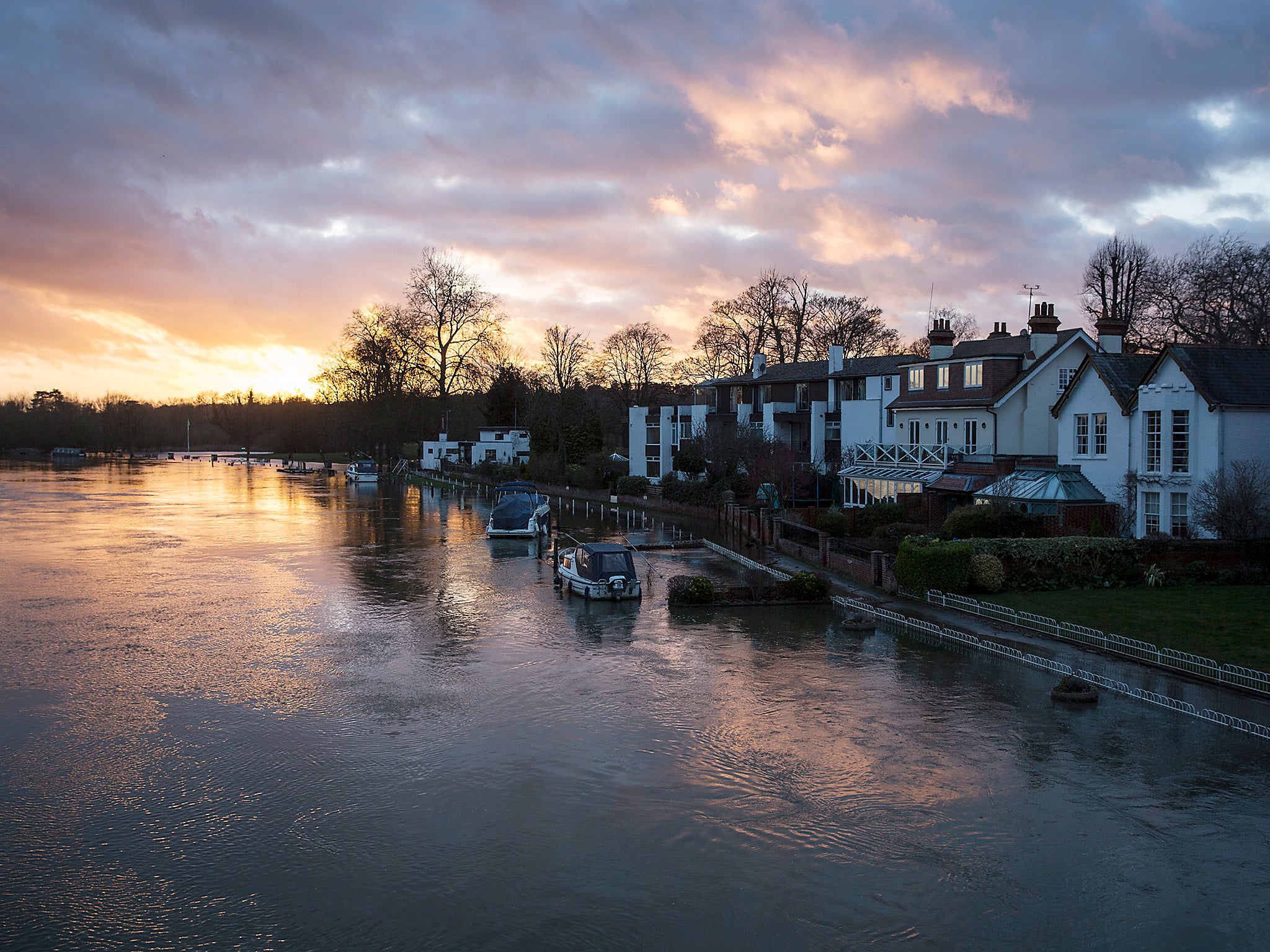 The sun sets behind the swollen river Thames which has burst its banks in Marlow, England