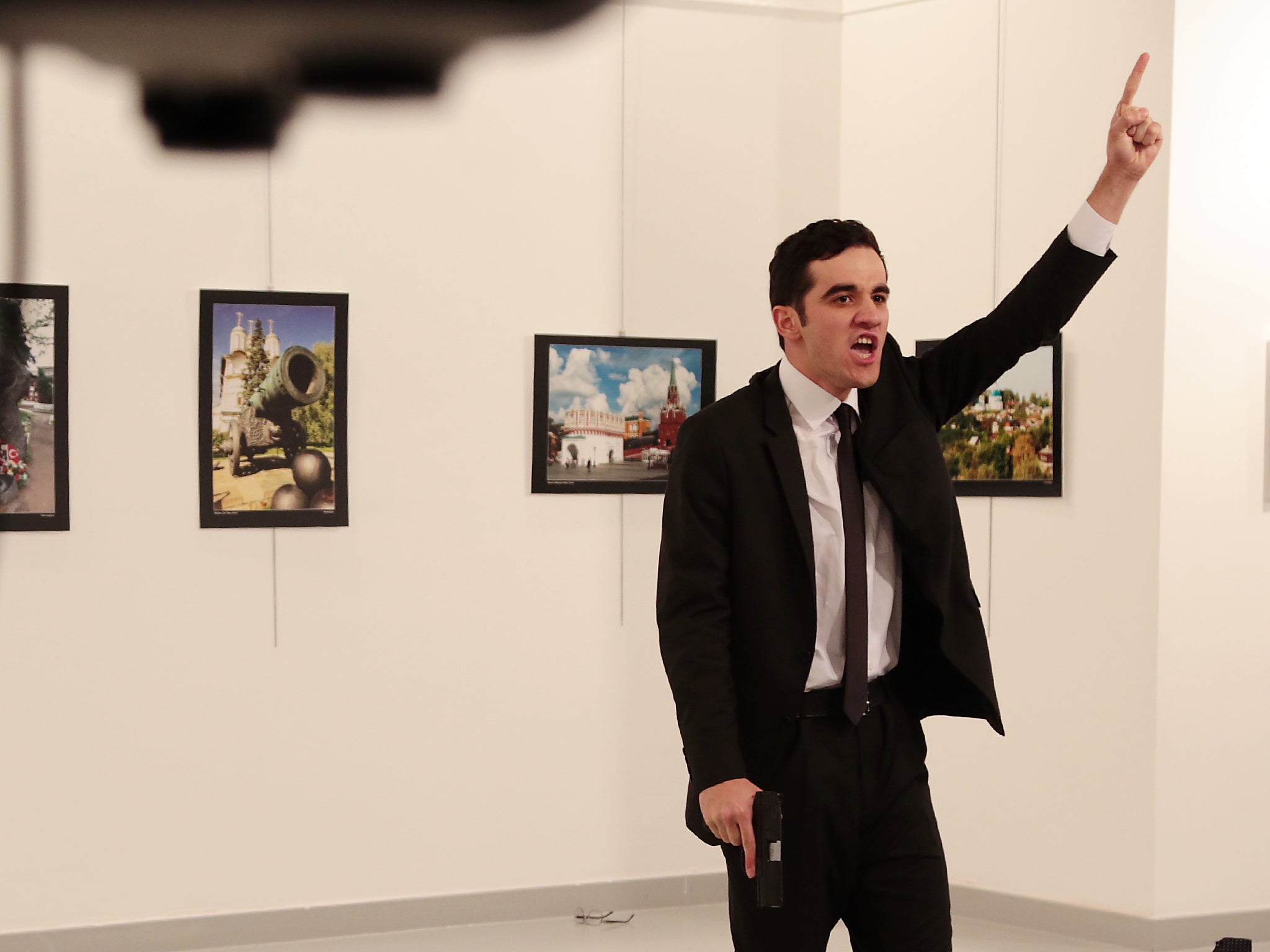 A man gestures near to the body of a man at a photo gallery in Ankara, Turkey