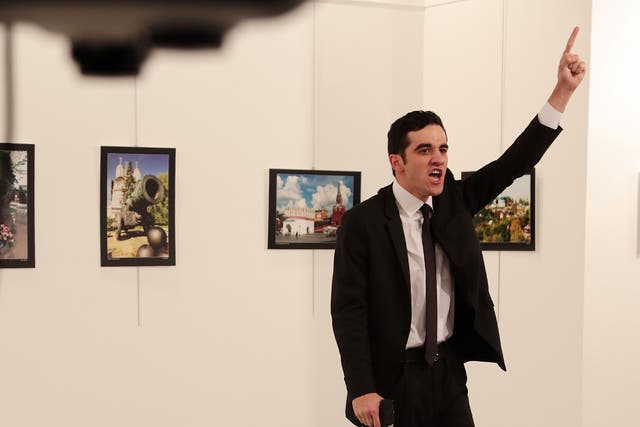 A man gestures near to the body of a man at a photo gallery in Ankara, Turkey