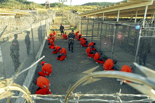 Taliban and al Qaeda detainees in orange jumpsuits in a holding area at Camp X-Ray at Naval Base Guantanamo Bay, Cuba