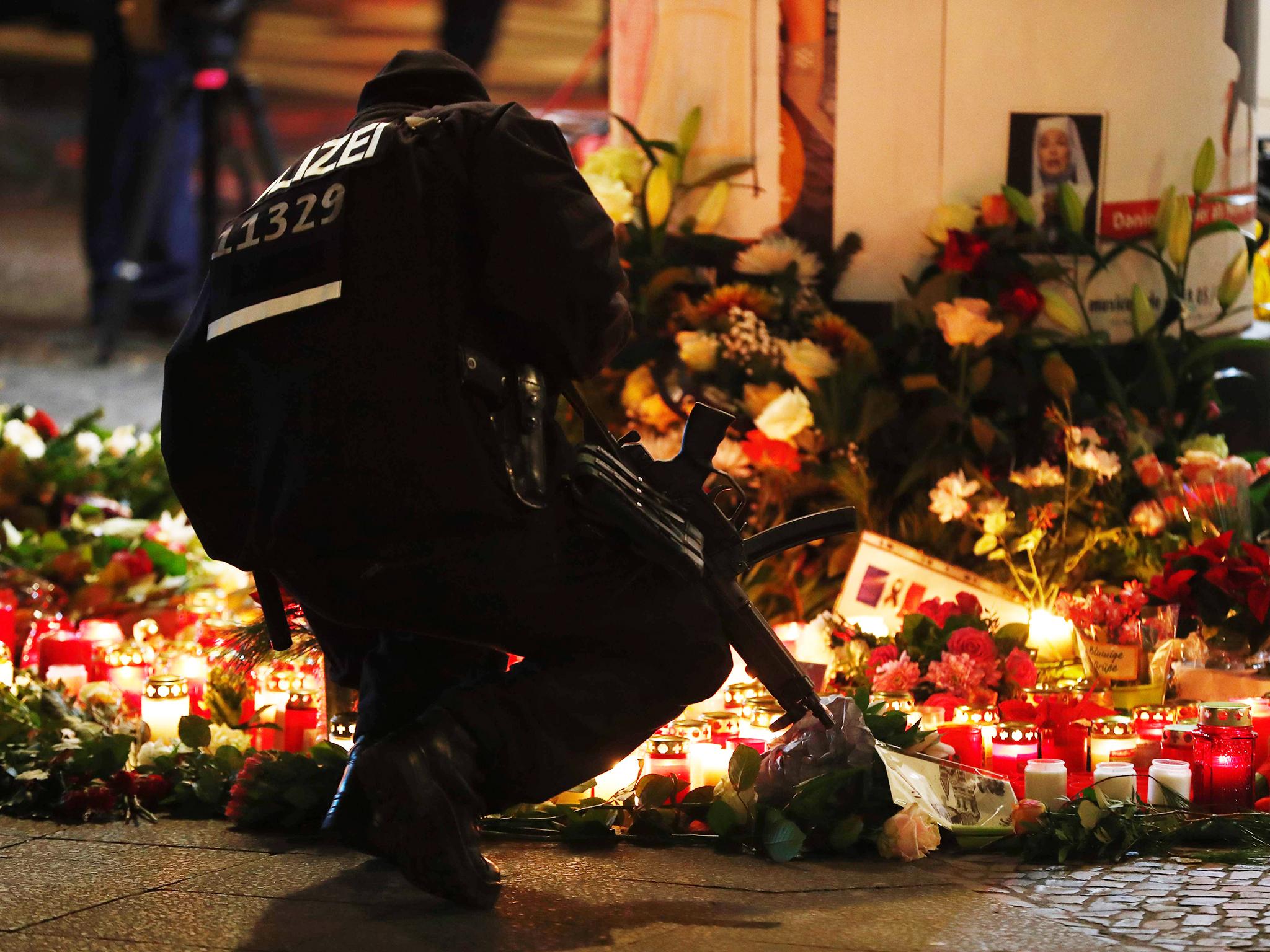 A policeman lights a candle at the makeshift memorial in front of the Kaiser Wilhelm Memorial Church on Tuesday