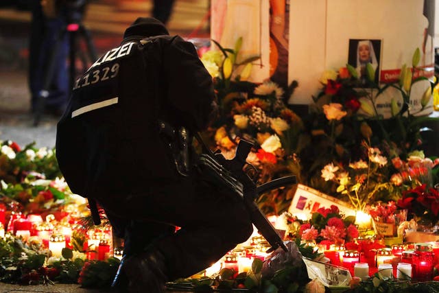 A policeman lights a candle at the makeshift memorial in front of the Kaiser Wilhelm Memorial Church on Tuesday