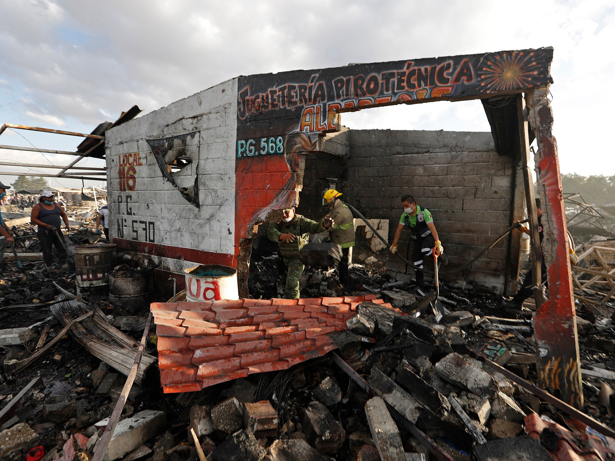Firefighters and rescue workers remove debris from the scorched ground of Mexico's fireworks market in Tultepec