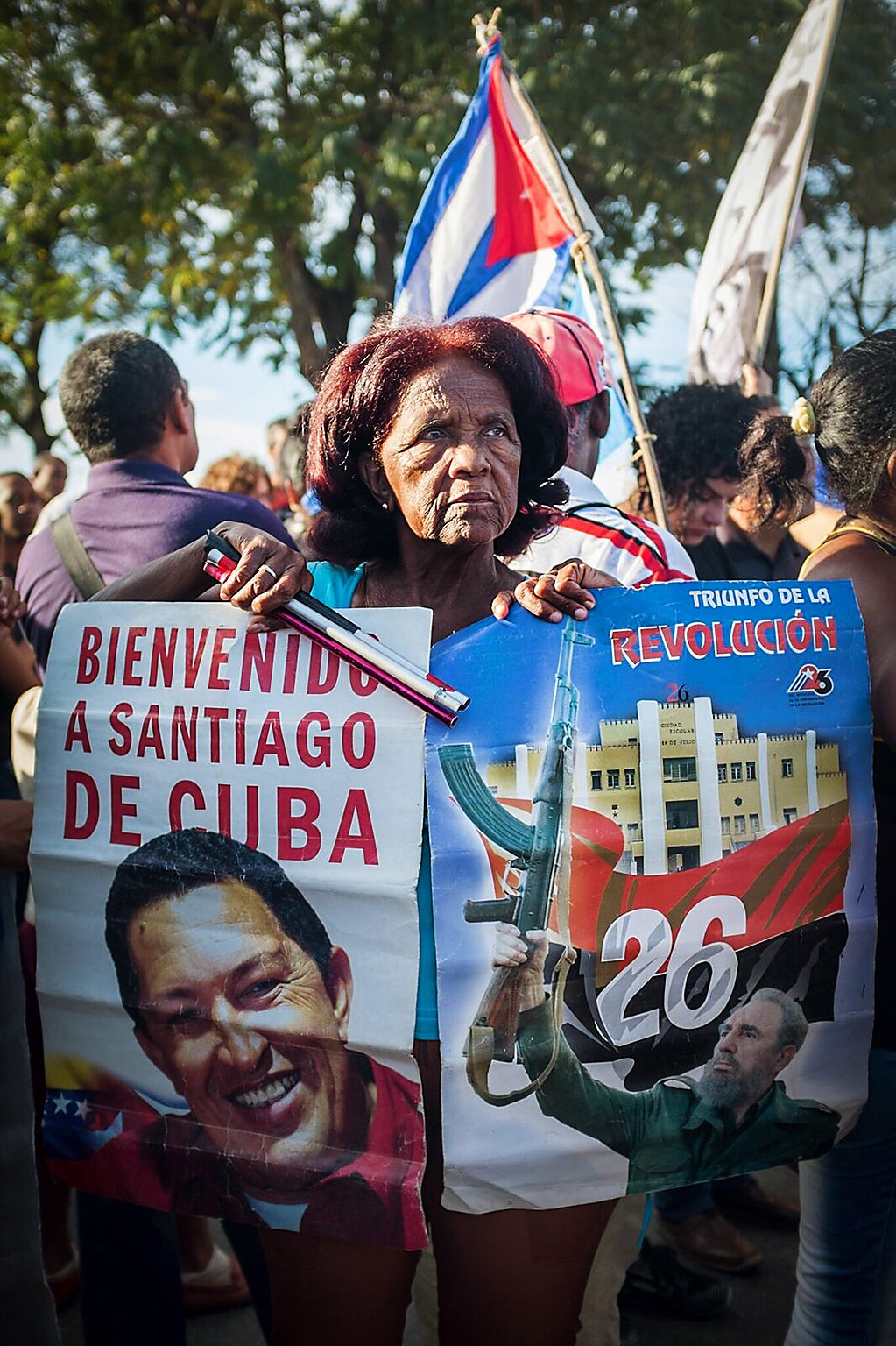 A Santiaguera poses with portraits of Hugo Chávez and Fidel Castro
