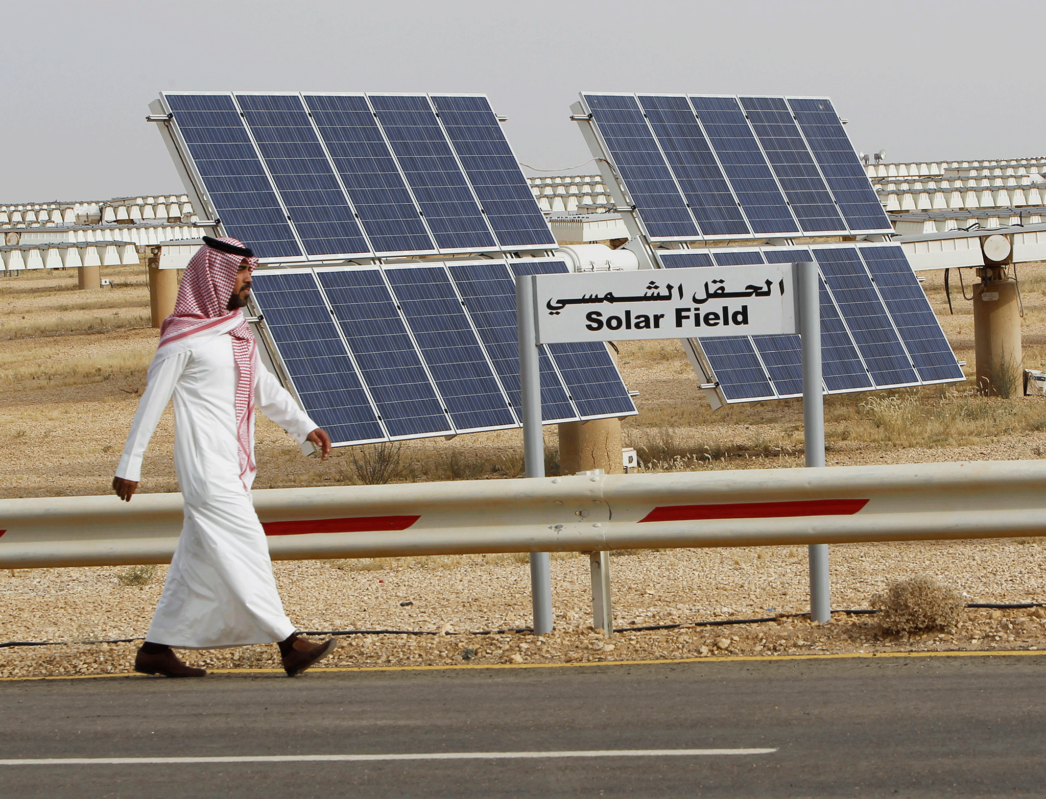 A man walks past a field of solar panels at the King Abdulaziz City of Sciences and Technology