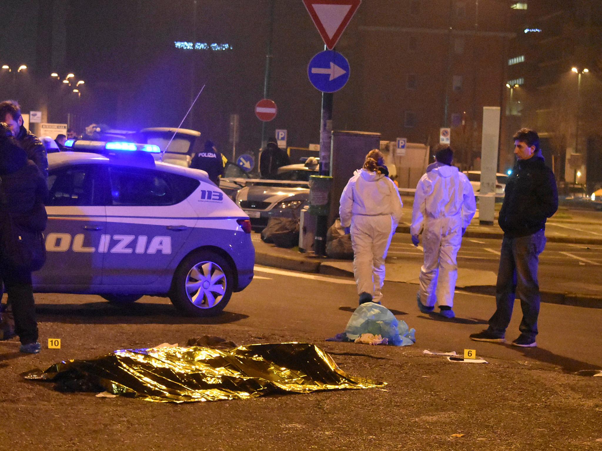 Italian police stands next to a covered body at the scene of a shootout between police and a man in Milan's Sesto San Giovanni neighbourhood, early 23 December 2016