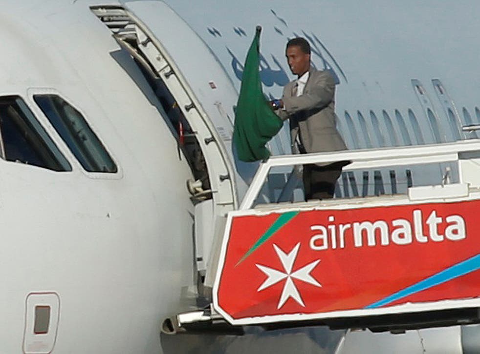 One of the hijackers of a Libyan Afriqiyah Airways Airbus A320 waves a Gaddafi-era Libyan flag at Malta Airport