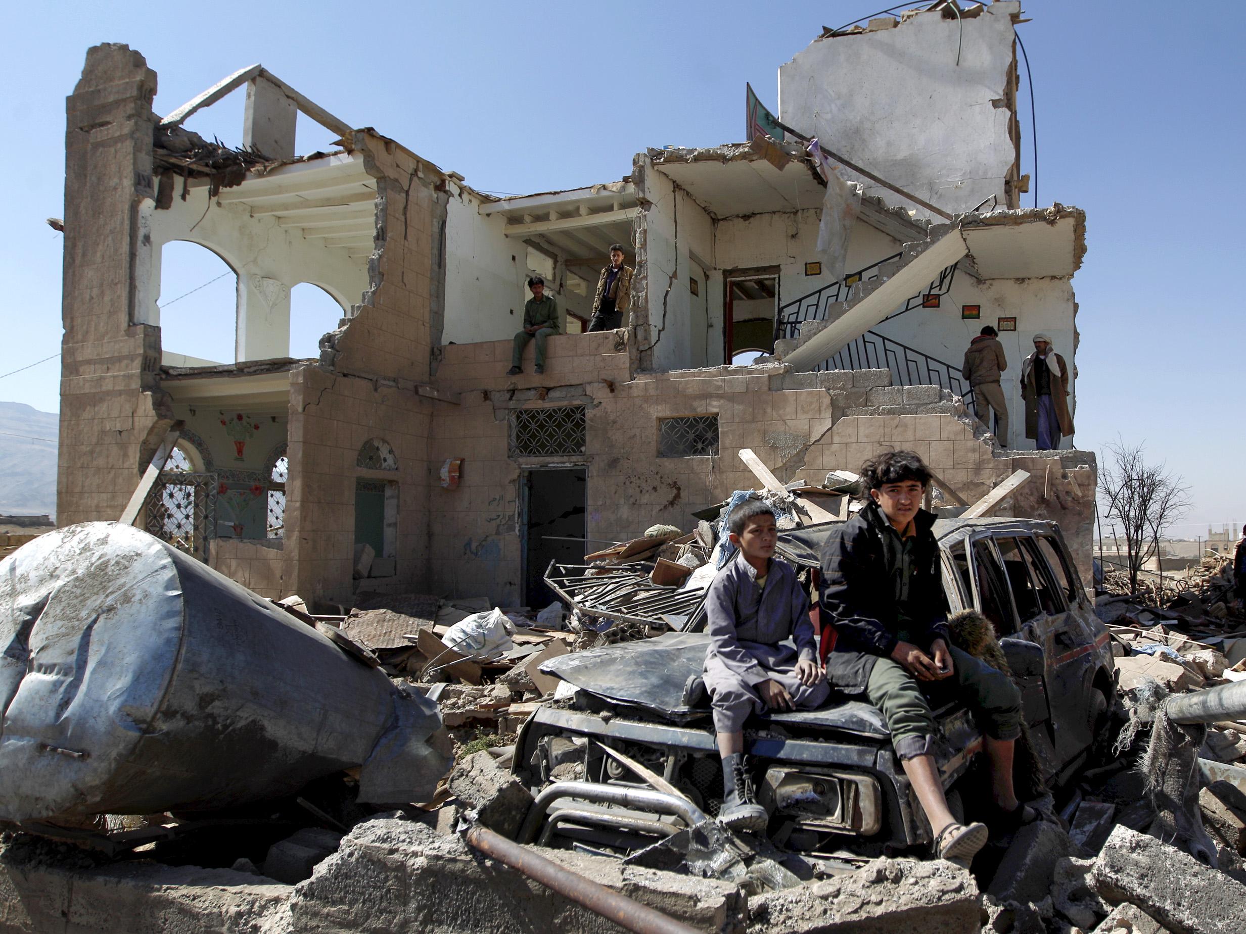 Children sit amid the rubble of a house hit by Saudi-led coalition airstrikes