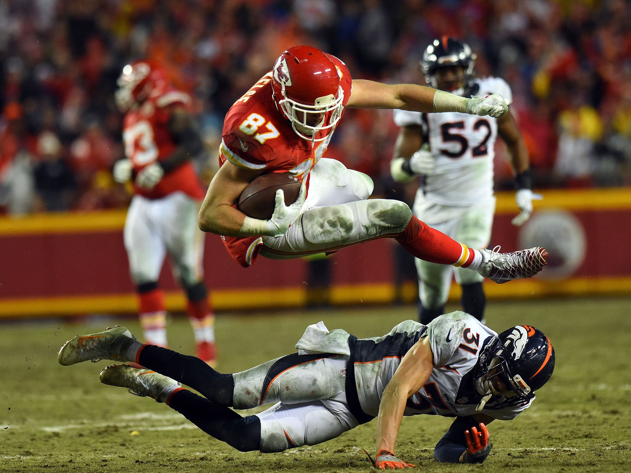 Travis Kelce of the Kansas City Chiefs hurdles over Denver Broncos safety Justin Simmons