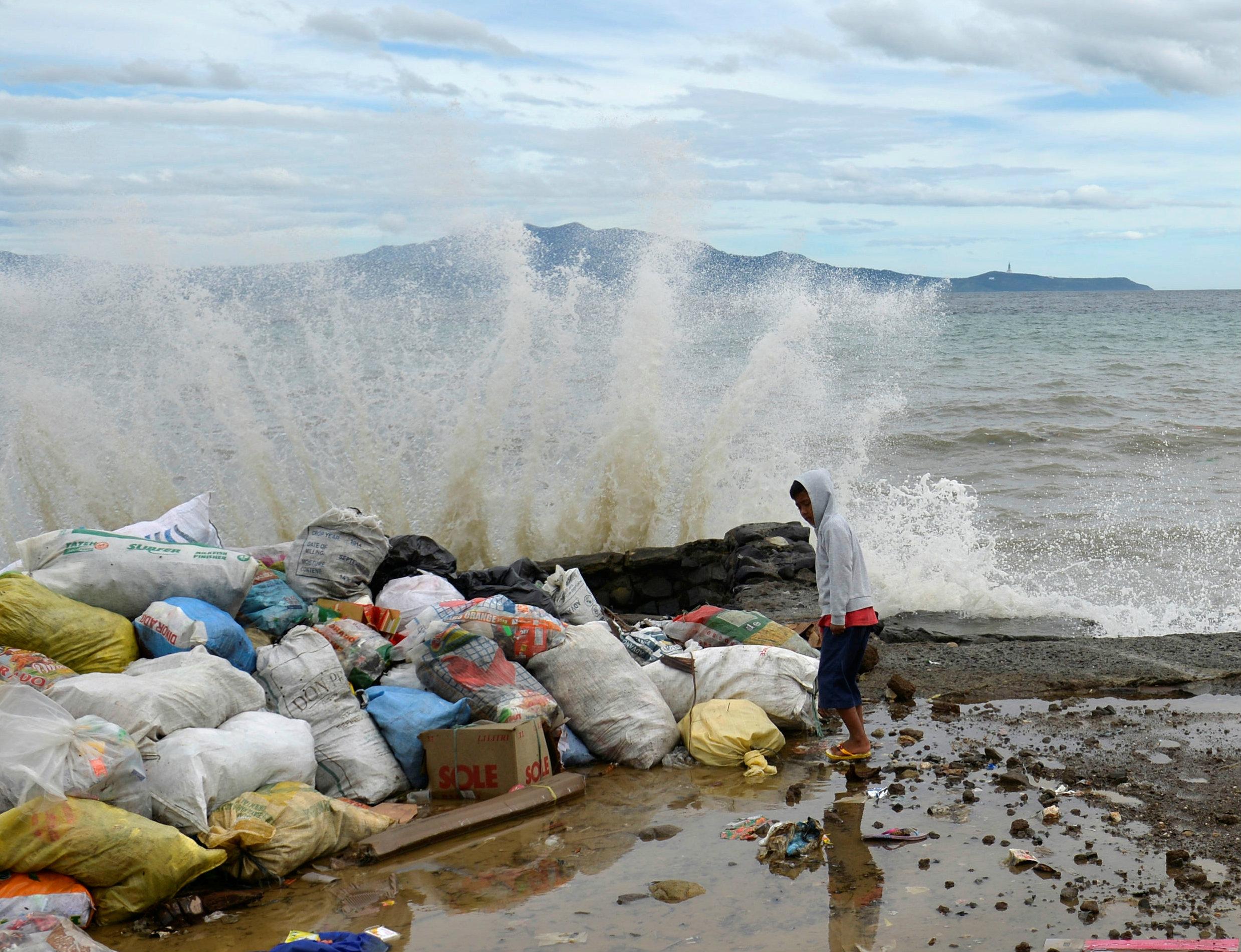 A boy stands at a partially damaged port, as strong waves hit the shore after Typhoon Nock-Ten hit Mabini, Batangas, in the Philippines