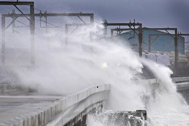 A Scotrail train passes,as waves crash against the new weather defences at Saltcoats railway station on December 23