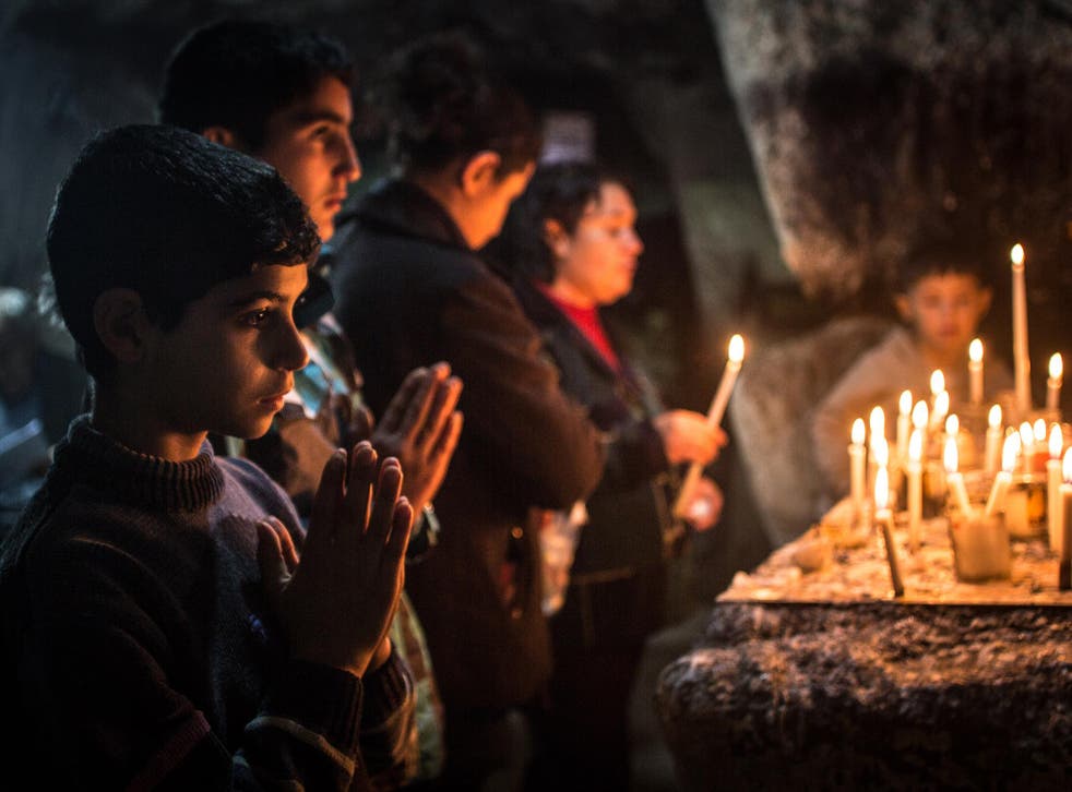 Iraqi Christians light candles inside a shrine in the grounds of Mazar Mar Eillia Catholic Church, which has now become home to hundreds of Iraqi Christians who were forced to flee their homes as Isis advanced towards them, 12 December, 2014 in Erbil, Iraq.