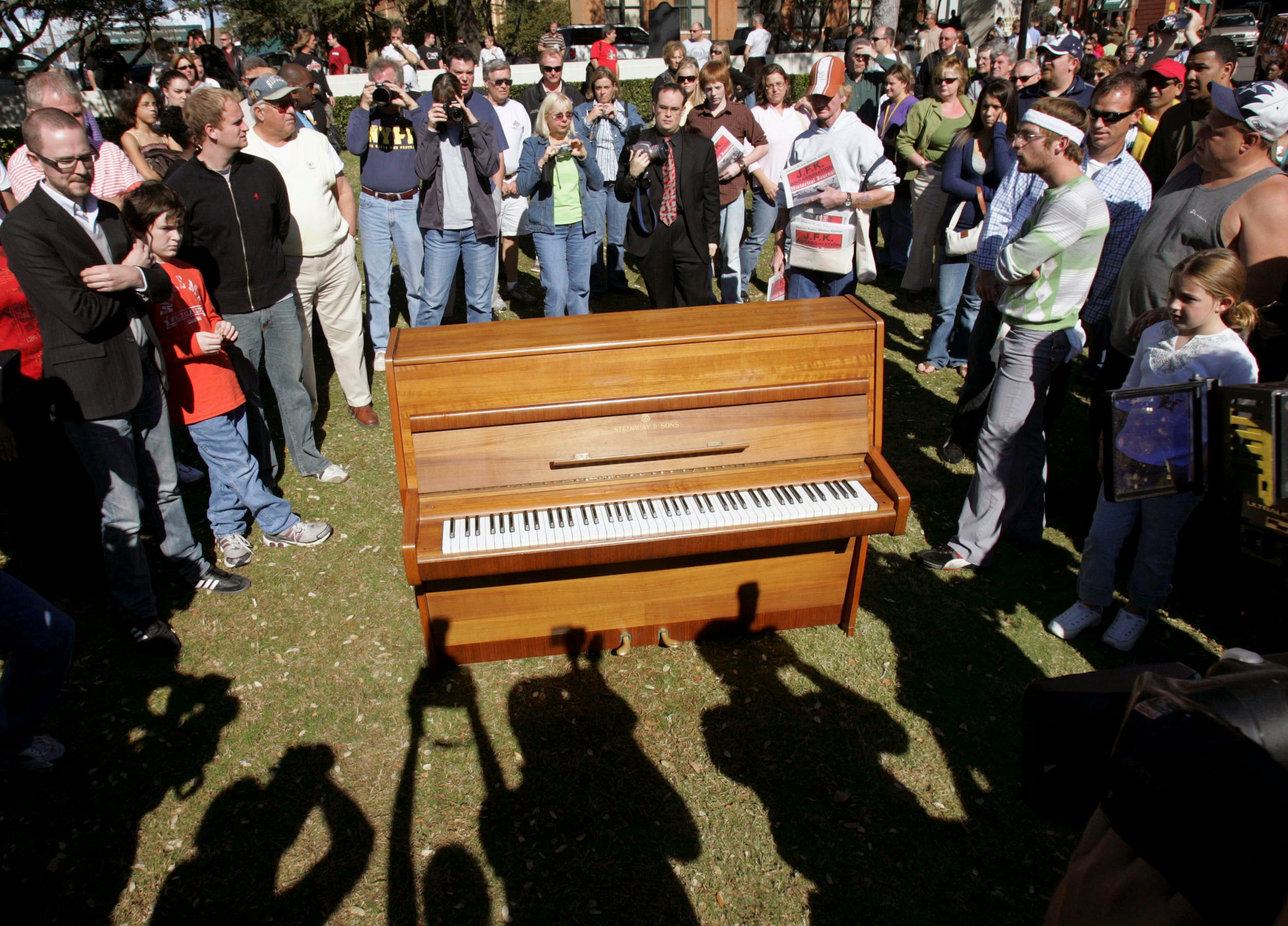 People gather around the piano which John Lennon used to compose the song 'Imagine'