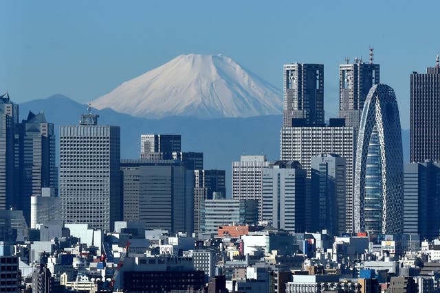 Japan's highest mountain, Mount Fuji (C) is seen behind the skyline of the Shinjuku area of Tokyo on December 6, 2014