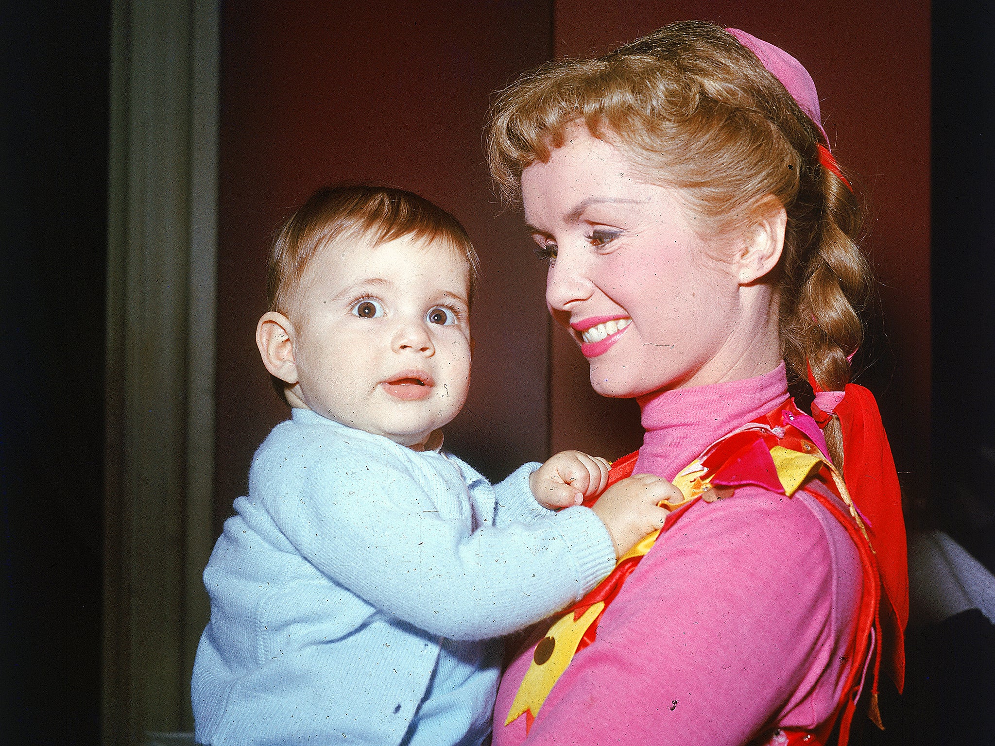 American actor and singer Debbie Reynolds smiles and holds her infant daughter, Carrie Fisher