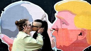  A lesbian couple kisses in front of mural depicting Russian President Vladimir Putin and Republican presidential candidate Donald Trump, on the walls of a barbecue bar 'Keule Ruke' on May 19, 2016 in Vilnius, Lithuania.
