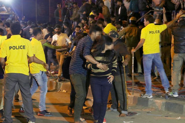A man helps a woman leave as police try to manage crowds during New Year's Eve celebrations in Bangalore