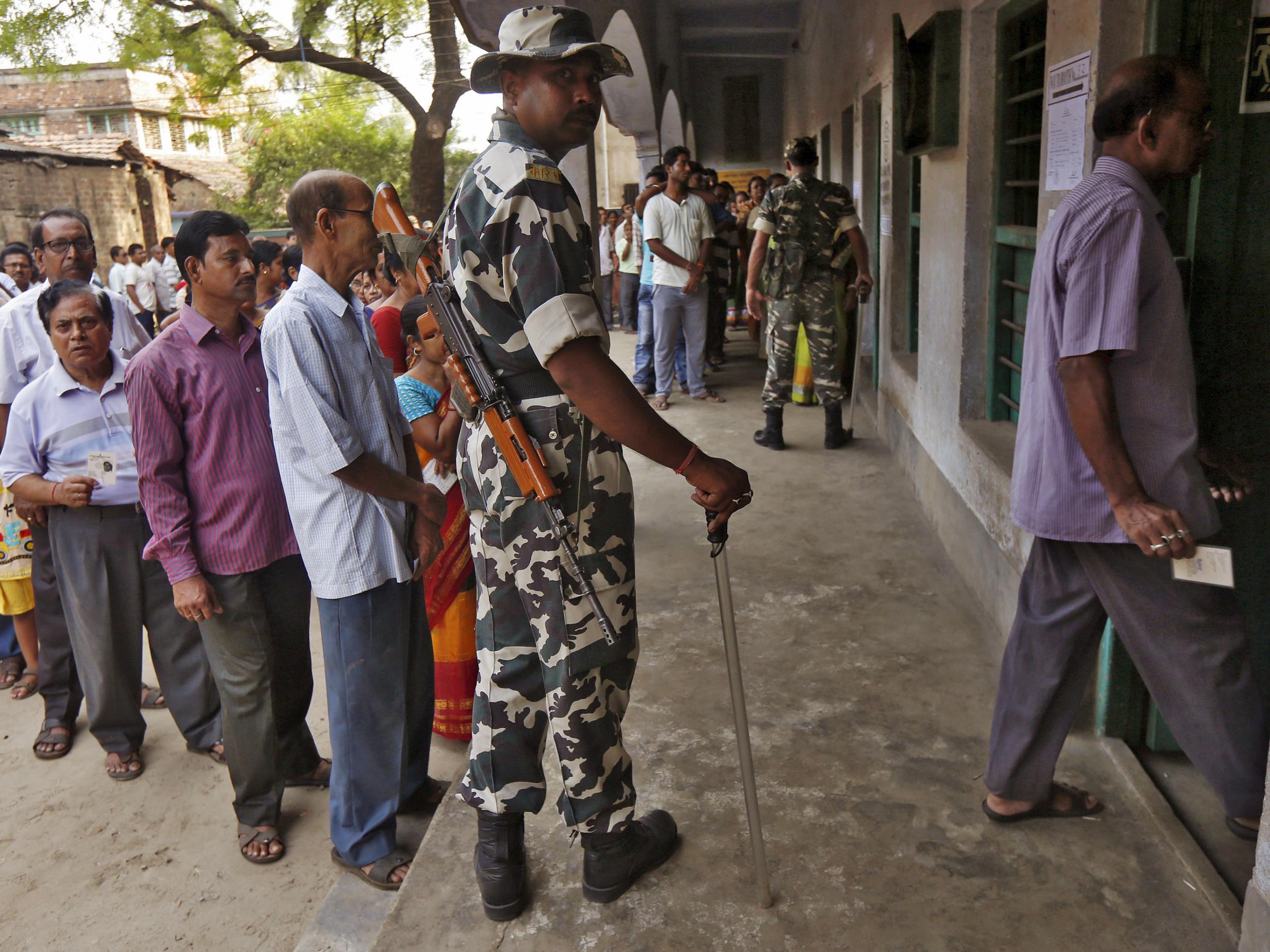 A policeman looks on as voters line up to cast their vote at a polling station during the fourth phase of West Bengal Assembly elections on the outskirts of Kolkata, India, April 25, 2016