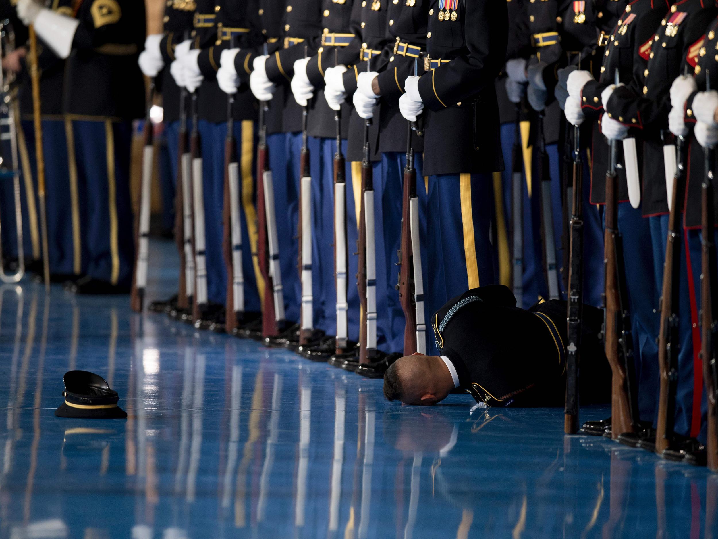 A member of the US Army Honor Guard lies on the floor after passing out during an Armed Forces Full Honor Farewell Review for US President Barack Obama