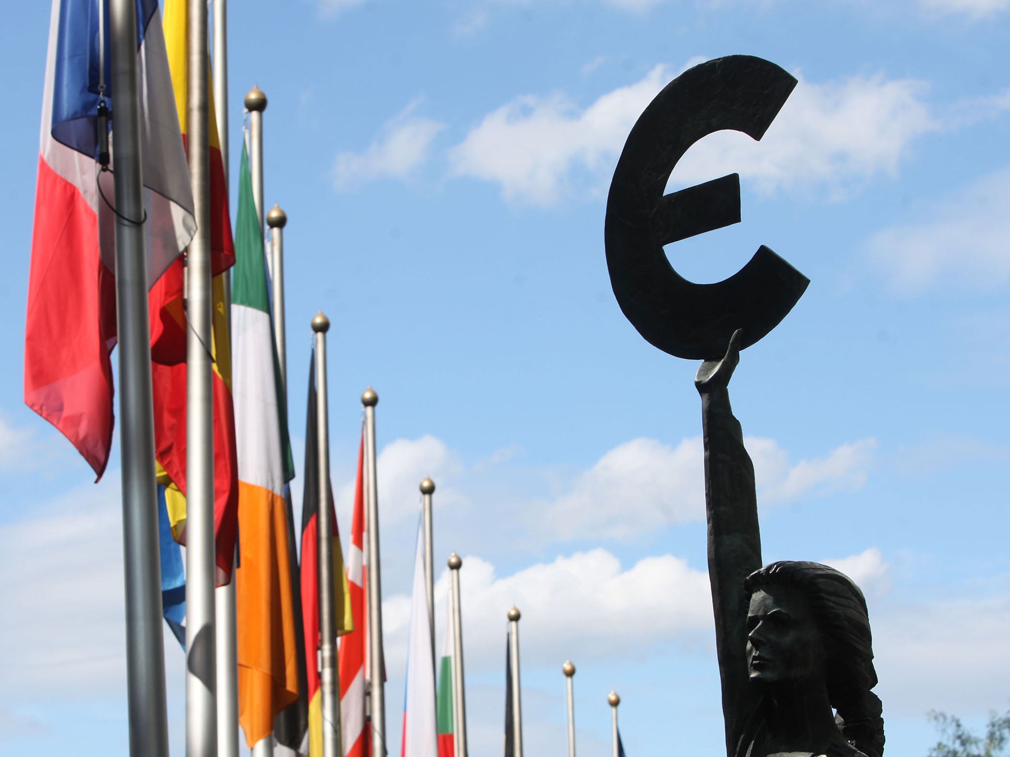 A statue holding the symbol of the Euro, the European common currency, stands in front of the European Parliament building