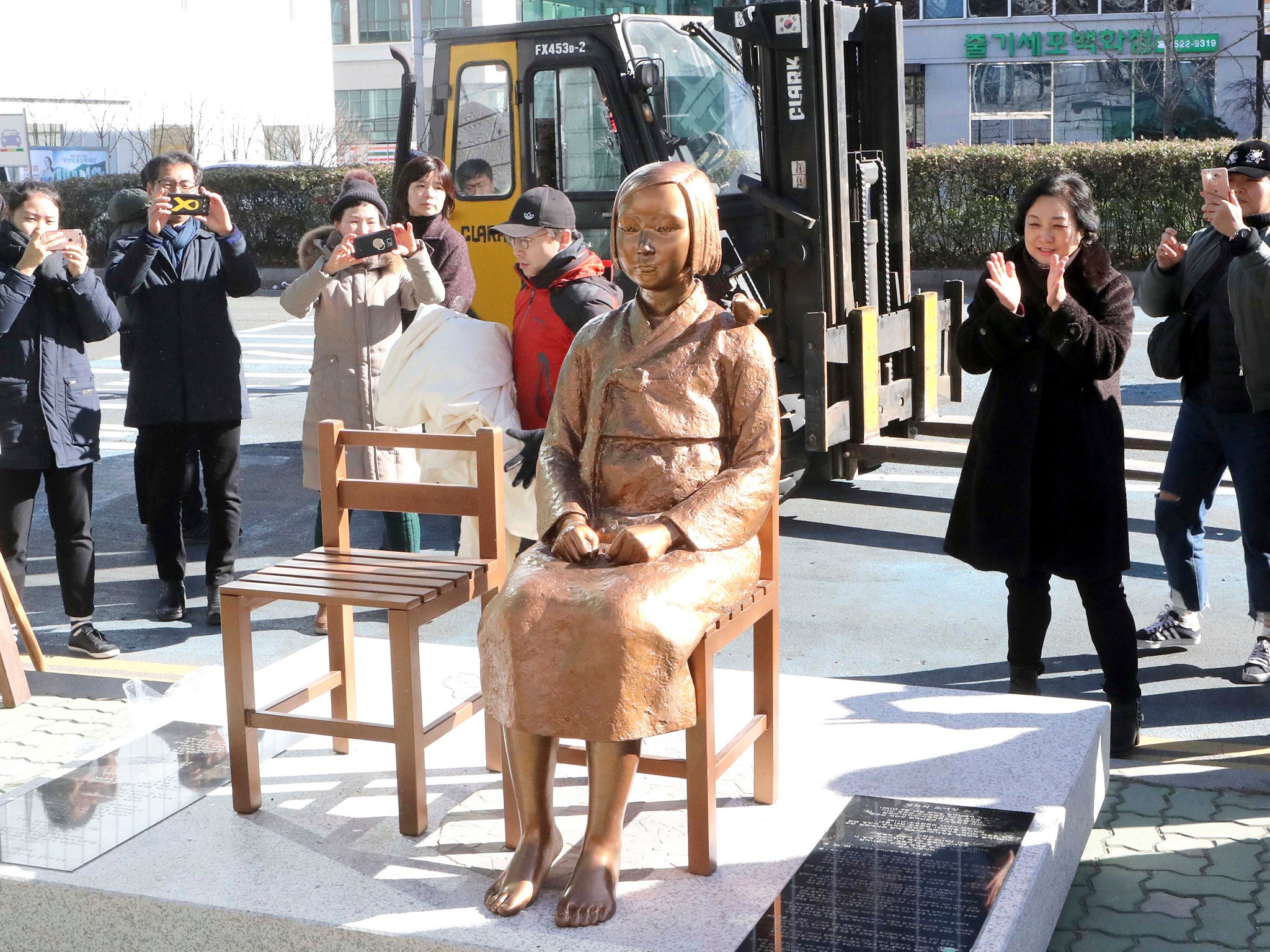 South Koreans take photos of a comfort-woman statue set up in front of the Japanese consulate in Busan