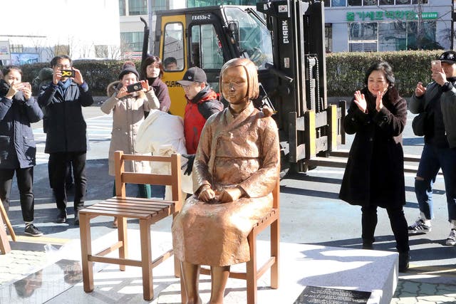 South Koreans take photos of a comfort-woman statue set up in front of the Japanese consulate in Busan