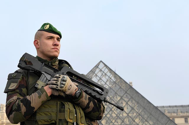 A soldier stands guard at the entrance of the Louvre museum in Paris