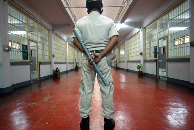 A prison police stands guard with a baton in the sleeping quarters of Bangkok's Klong Prem Prison