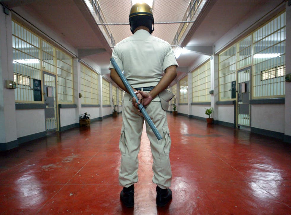 A prison police stands guard with a baton in the sleeping quarters of Bangkok's Klong Prem Prison
