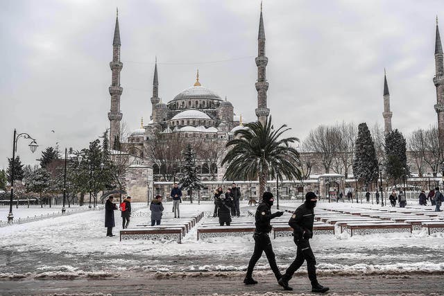 Snowfall offers a moment of peace, as anti-riot police officers patrol around the Blue mosque (Sultan Ahmet)