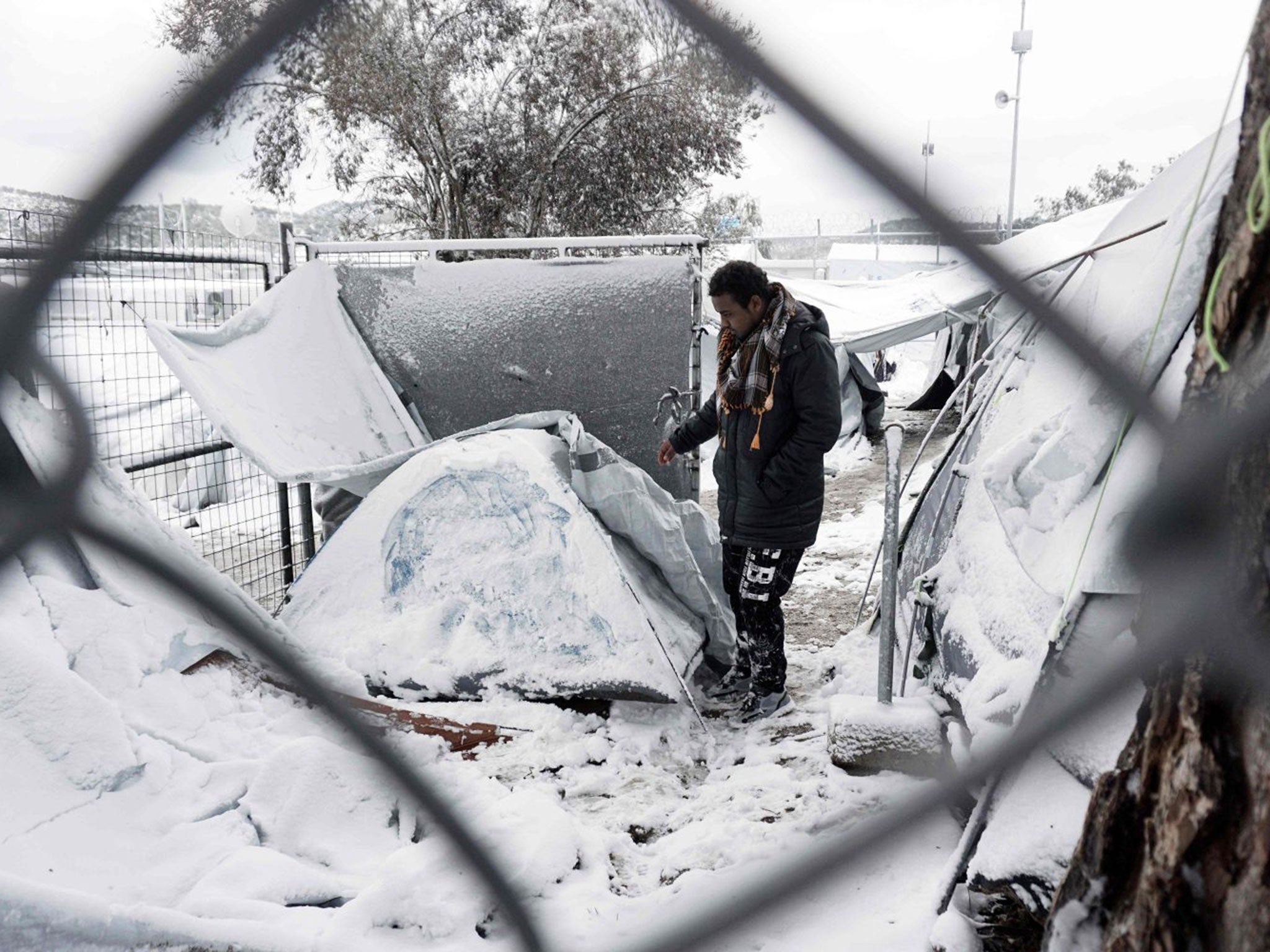 A migrant stands next to a snow-covered tent at the Moria detention camp on the Greek island of Lesbos on 7 January