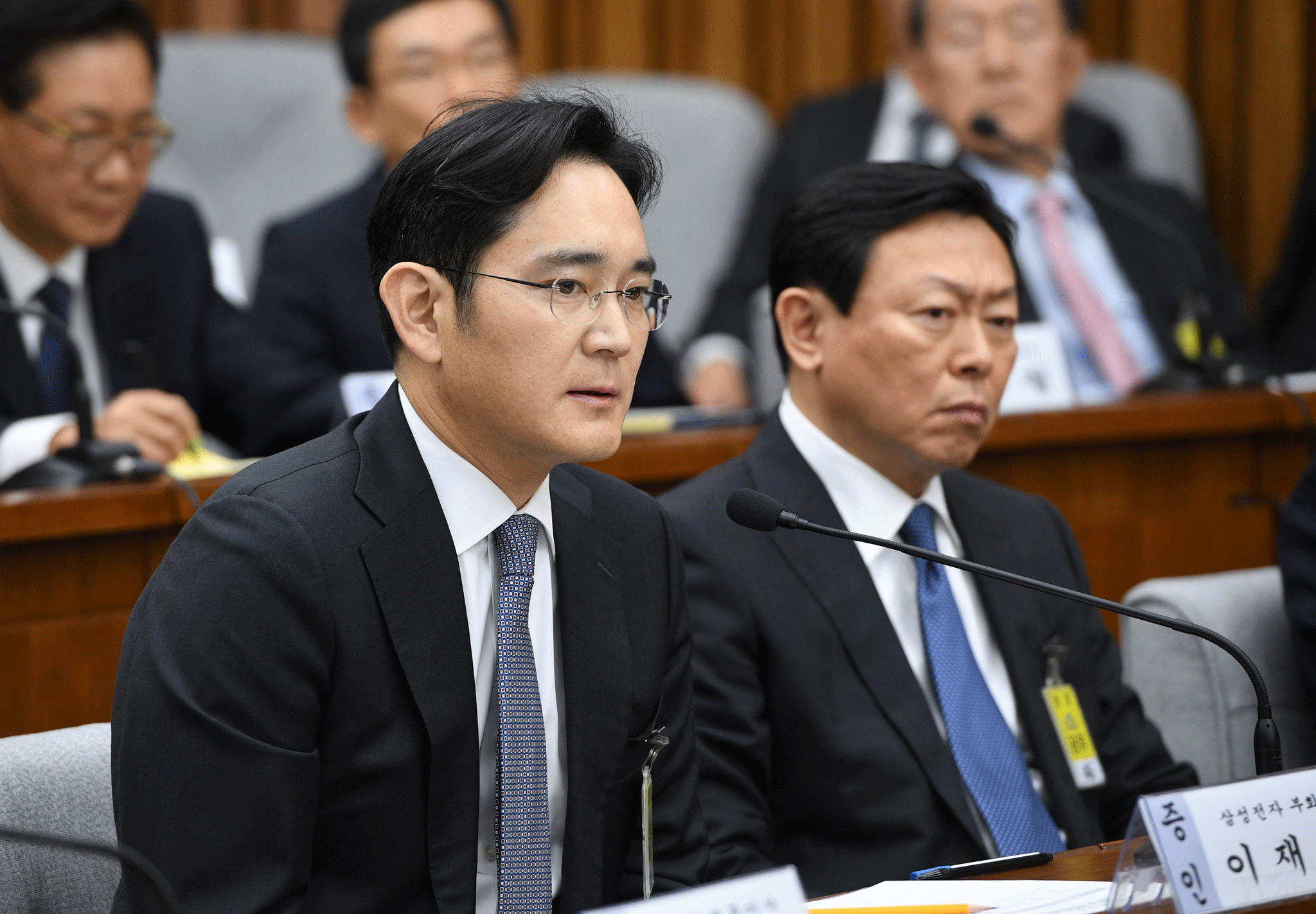 Samsung Group's heir-apparent Lee Jae-yong (L) answers a question as Lotte Group Chairman Shin Dong-Bin (R) listens during a parliamentary probe into a scandal engulfing President Park Geun-Hye at the National Assembly in Seoul on December 6, 2016