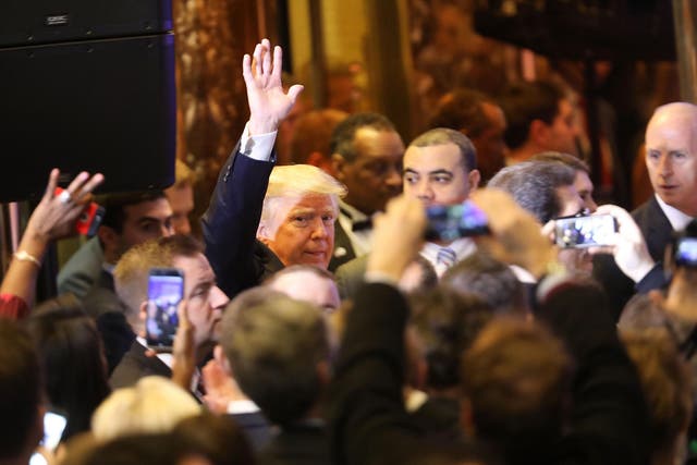 Mr Trump walks among the throng of reporters at onlookers at Trump Tower