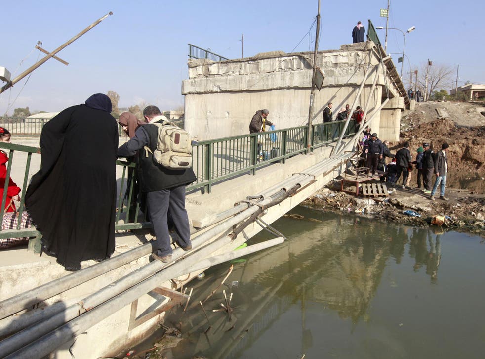 Displaced people who fled Isis militants cross the bridge in Al-Muthanna neighbourhood of Mosul