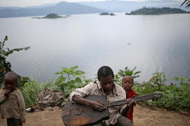 Mwenyezi, 36, plays a guitar at Kagorwa Pygmy camp on Idjwi island in the Democratic Republic of Congo