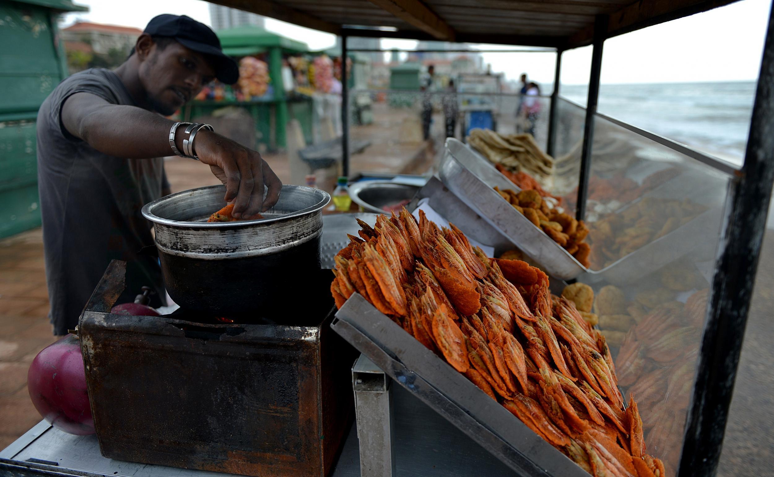 A vendor sells street snack isso vadei on Galle Face Beach